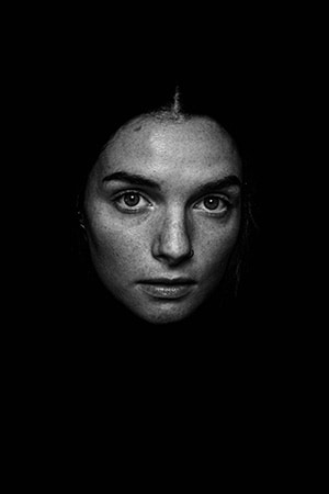 Black & white portrait: Woman with intense gaze (dark background)