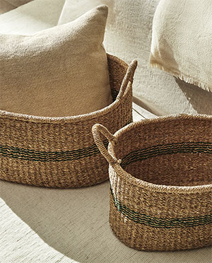 Woven baskets (green stripes) on textured mat (sunlight, pillows)