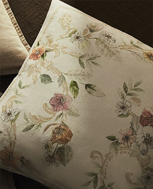 Floral pillow (pink, green, brown) on dark fabric (soft light)