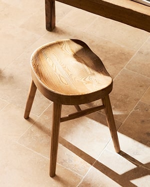 Curved wood stool on tiled floor (natural light, shadow)
