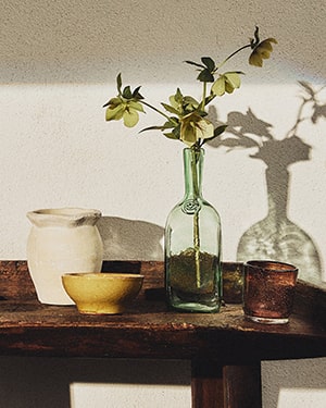 Small table: green bottle (leaves), white jar, yellow bowl, brown cup