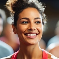 A joyful woman wearing a red tank top with her hair in a bun.