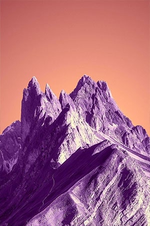 Surreal mountainscape: Jagged peaks against purple & orange sky